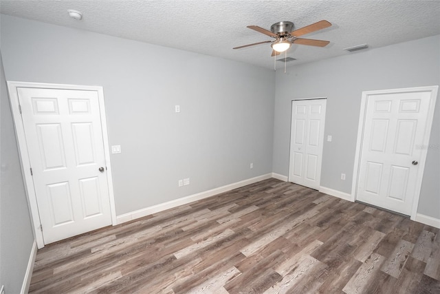 unfurnished bedroom featuring a textured ceiling, dark wood-type flooring, and ceiling fan