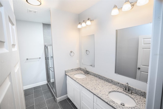 bathroom featuring a textured ceiling, vanity, and an enclosed shower