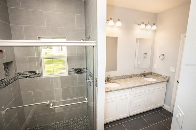 bathroom featuring tile patterned flooring, a shower with shower door, and vanity