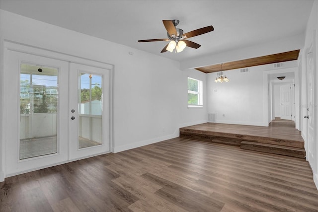 empty room featuring ceiling fan with notable chandelier, plenty of natural light, hardwood / wood-style floors, and french doors