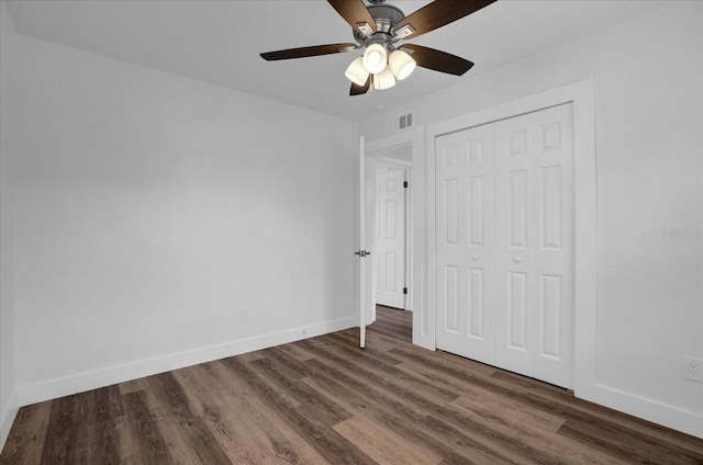 unfurnished bedroom with dark wood-type flooring, ceiling fan, and a closet