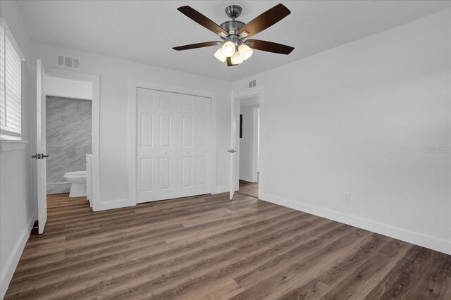 unfurnished bedroom with ceiling fan, a closet, dark hardwood / wood-style floors, and ensuite bathroom