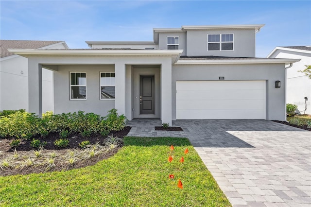 prairie-style house with decorative driveway, an attached garage, and stucco siding