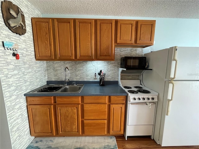 kitchen featuring a textured ceiling, dark hardwood / wood-style floors, white appliances, tasteful backsplash, and sink