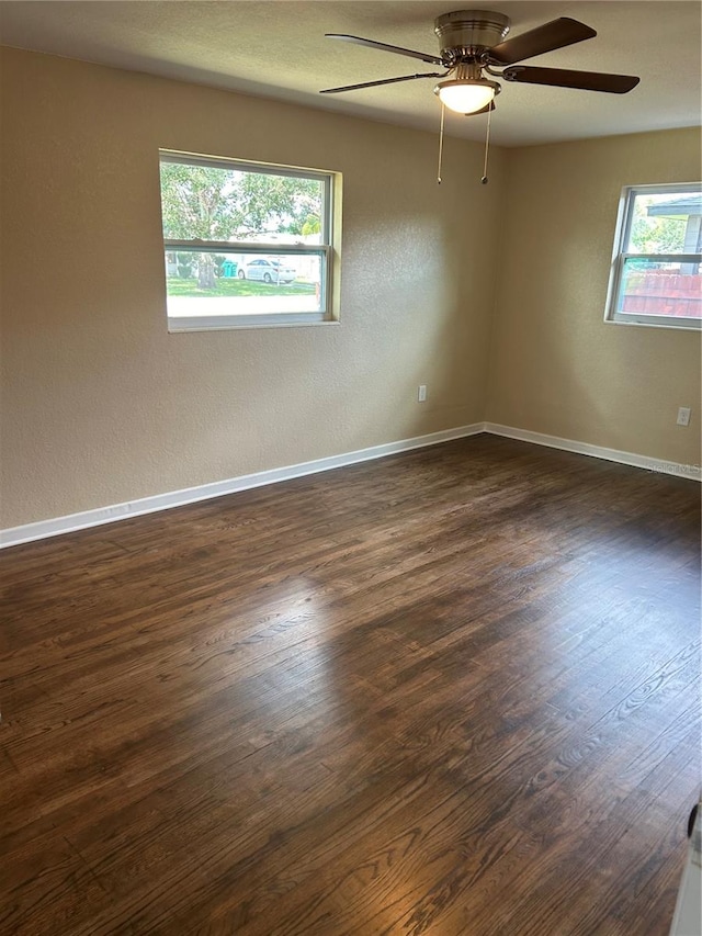 empty room with dark hardwood / wood-style floors, ceiling fan, and plenty of natural light