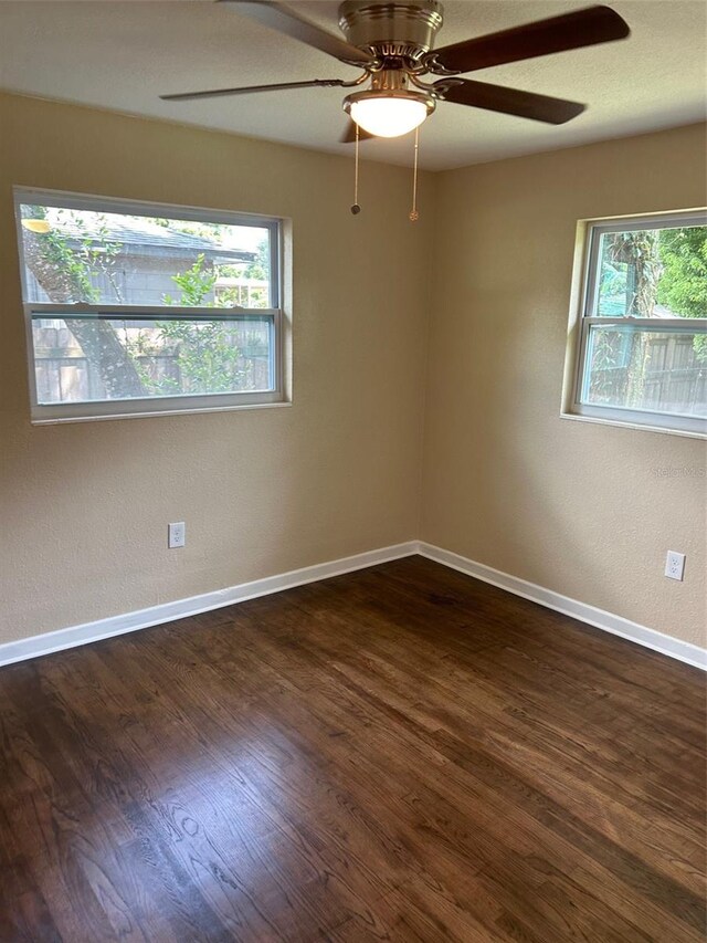 spare room featuring ceiling fan, a healthy amount of sunlight, and dark hardwood / wood-style flooring