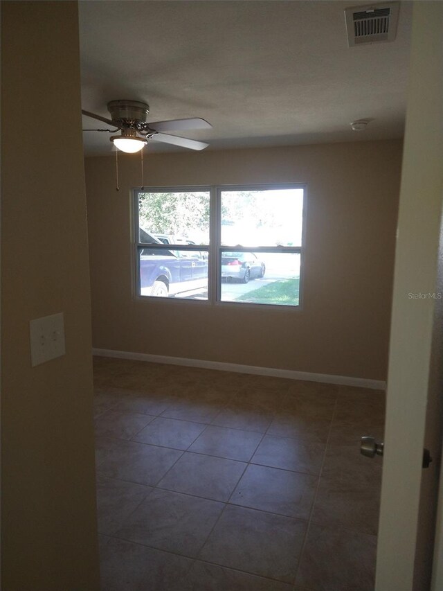 empty room featuring dark tile patterned flooring and ceiling fan