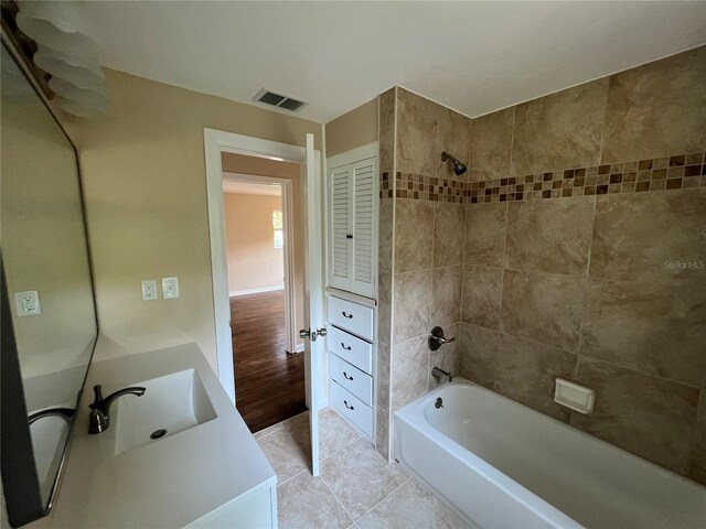 bathroom with wood-type flooring, tiled shower / bath, and vanity