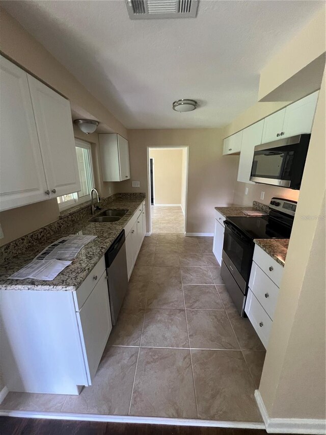 kitchen featuring appliances with stainless steel finishes, sink, light tile patterned floors, and white cabinets