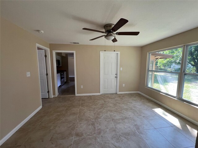 unfurnished bedroom featuring a spacious closet, a closet, ceiling fan, and light tile patterned floors