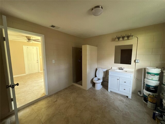 bathroom featuring ceiling fan, vanity, walk in shower, tile walls, and toilet