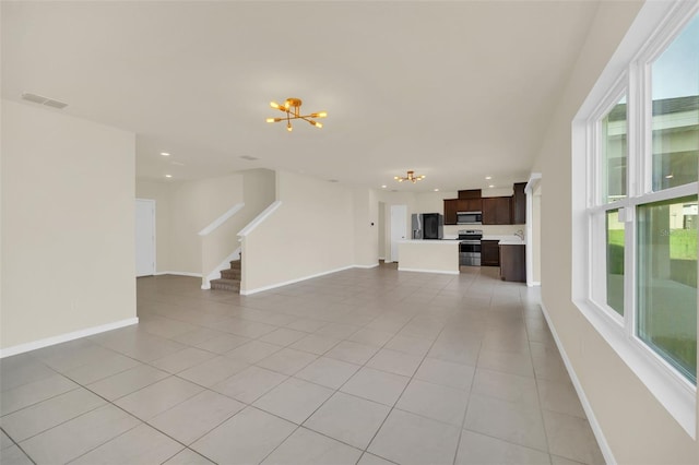 unfurnished living room with an inviting chandelier and light tile patterned floors