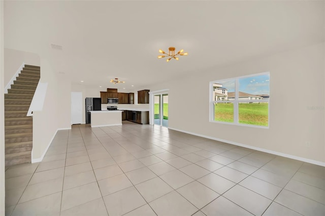 unfurnished living room with a notable chandelier and light tile patterned flooring