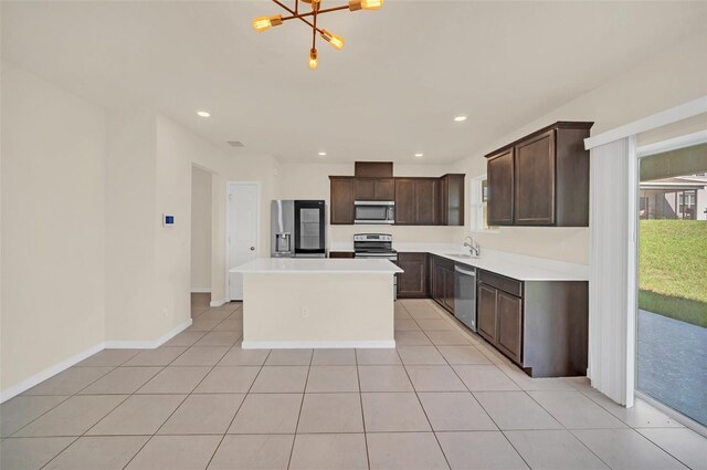 kitchen featuring a kitchen island, stainless steel appliances, dark brown cabinets, sink, and a chandelier