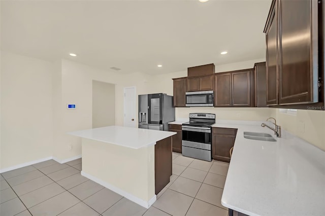 kitchen with appliances with stainless steel finishes, a kitchen island, light tile patterned floors, dark brown cabinetry, and sink