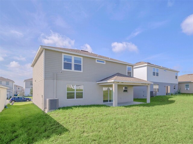 rear view of property with a yard, a patio, and central AC