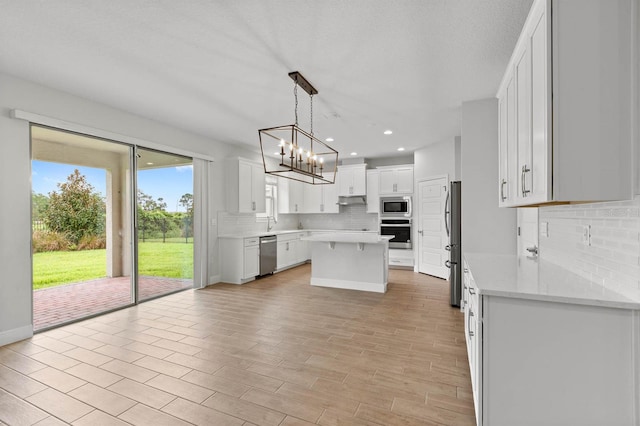 kitchen featuring white cabinetry, a center island, stainless steel appliances, and plenty of natural light