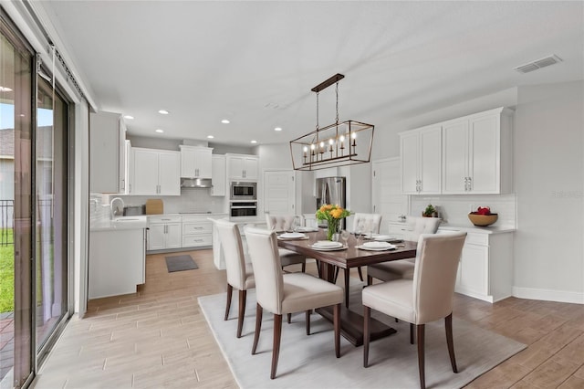 dining room with sink, a chandelier, light hardwood / wood-style floors, and a wealth of natural light