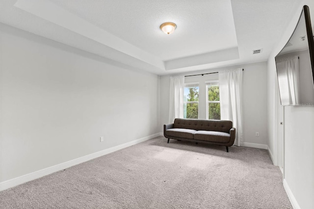 living area featuring a raised ceiling and carpet flooring