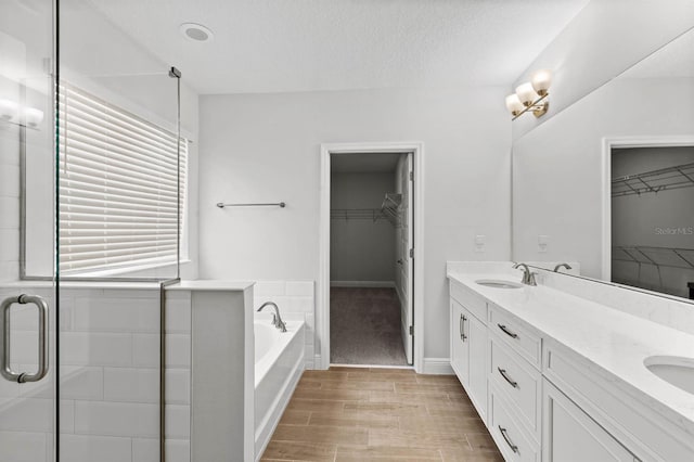 bathroom with a wealth of natural light, independent shower and bath, hardwood / wood-style flooring, and vanity