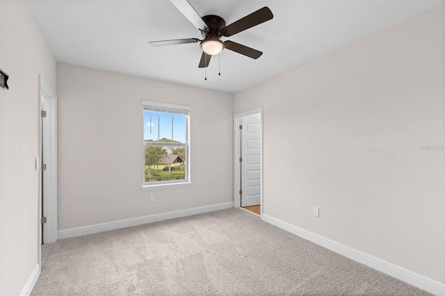 empty room featuring ceiling fan and light colored carpet