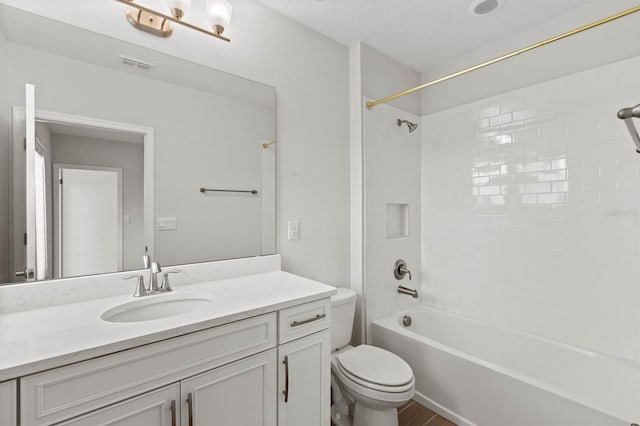 full bathroom featuring a textured ceiling, tiled shower / bath combo, vanity, and toilet