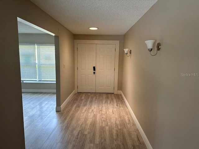 hall featuring light hardwood / wood-style floors and a textured ceiling