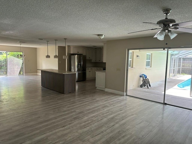 kitchen with stainless steel fridge, hanging light fixtures, a center island, and wood-type flooring