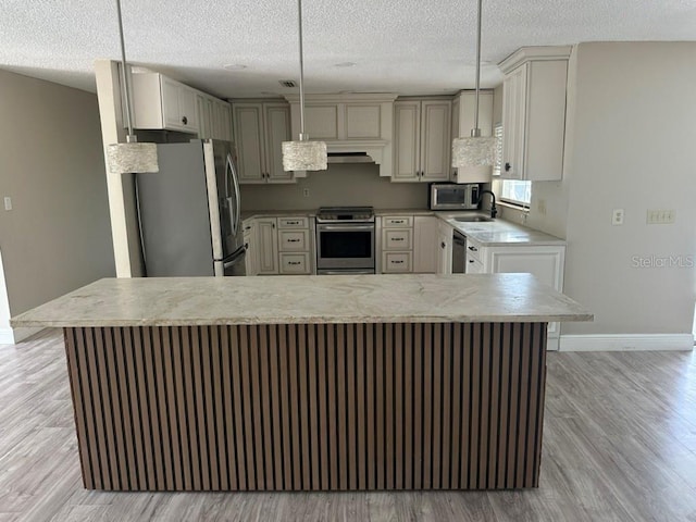 kitchen with appliances with stainless steel finishes, light hardwood / wood-style flooring, a textured ceiling, and decorative light fixtures