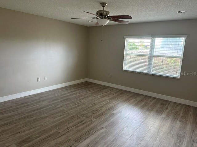 empty room with dark hardwood / wood-style floors, a textured ceiling, and ceiling fan