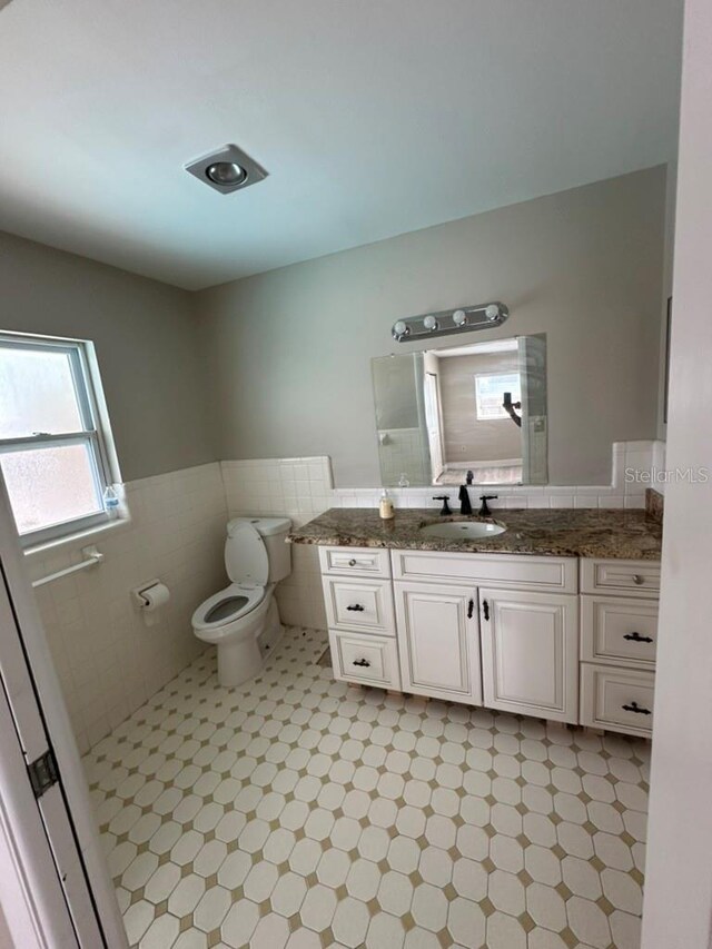 bathroom with tile walls, vanity, and toilet