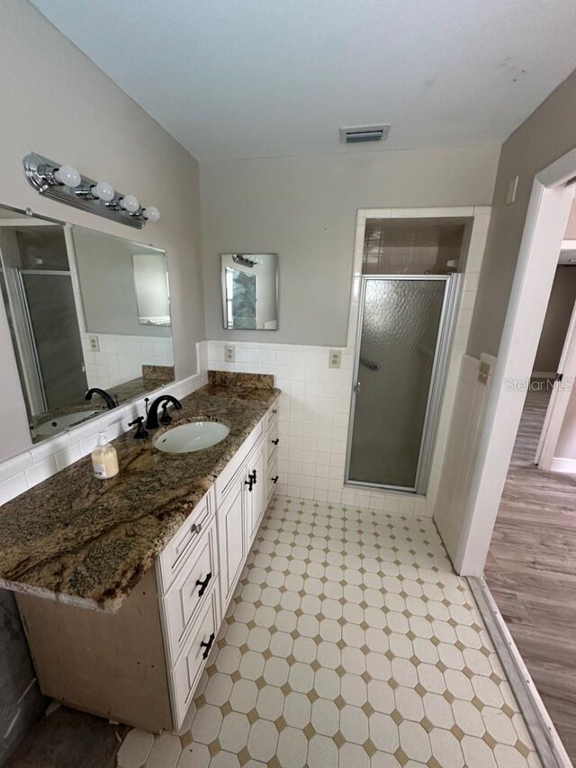 bathroom featuring vanity, an enclosed shower, and tile walls