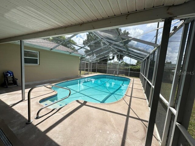 view of swimming pool with a patio area and a lanai