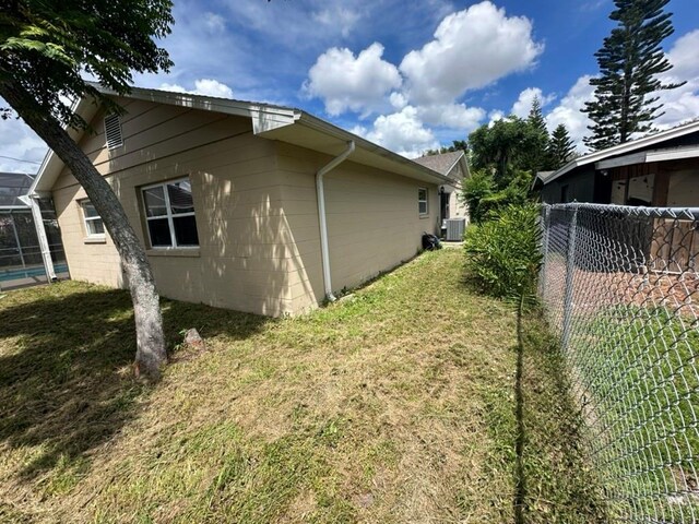 view of side of property featuring a yard and central AC unit