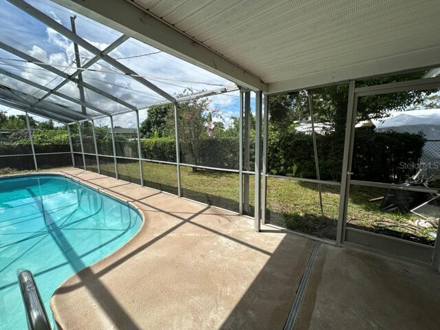 view of swimming pool featuring a patio, glass enclosure, and a lawn