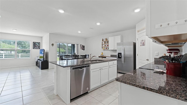 kitchen featuring white cabinets, sink, a center island with sink, appliances with stainless steel finishes, and dark stone countertops