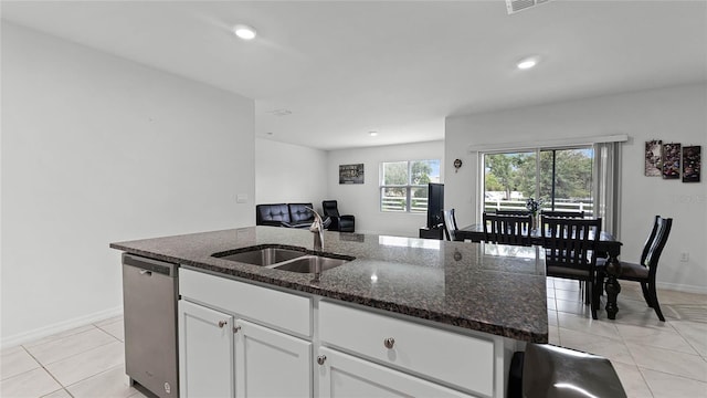 kitchen with dark stone countertops, an island with sink, white cabinets, dishwasher, and sink