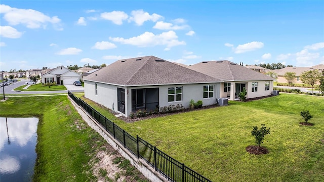 back of property featuring a yard, a water view, and central AC unit