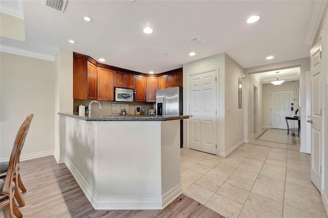 kitchen featuring kitchen peninsula, decorative backsplash, stainless steel appliances, light tile patterned floors, and crown molding