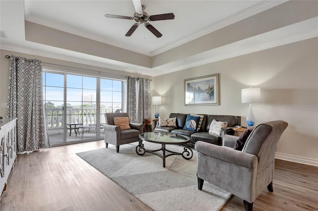 living room featuring ornamental molding, light hardwood / wood-style floors, and ceiling fan