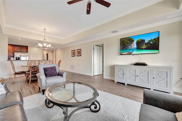 living room featuring ornamental molding, a tray ceiling, and light hardwood / wood-style floors