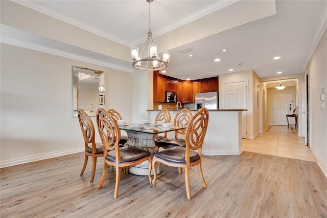 dining room featuring a notable chandelier, light wood-type flooring, and crown molding