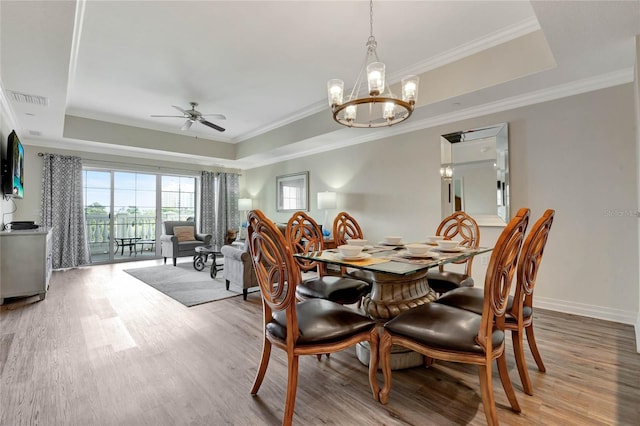 dining room featuring light hardwood / wood-style flooring, crown molding, and a raised ceiling