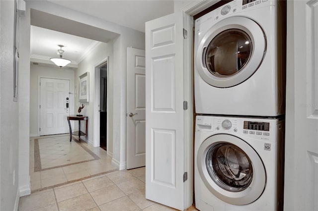 washroom with stacked washer / dryer, ornamental molding, and light tile patterned floors