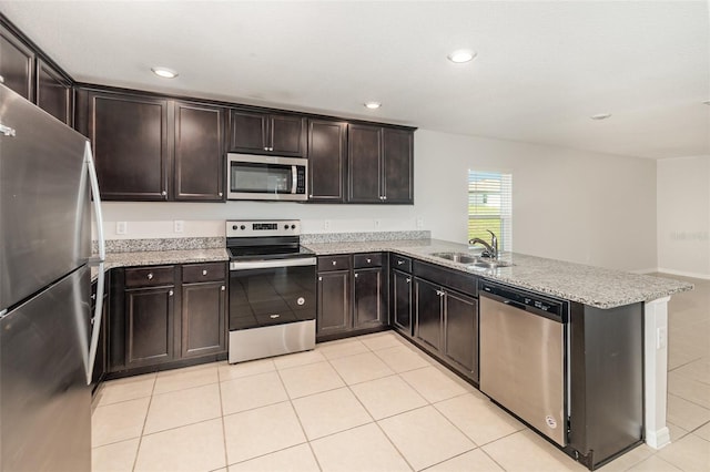 kitchen featuring dark brown cabinets, stainless steel appliances, light stone counters, and kitchen peninsula