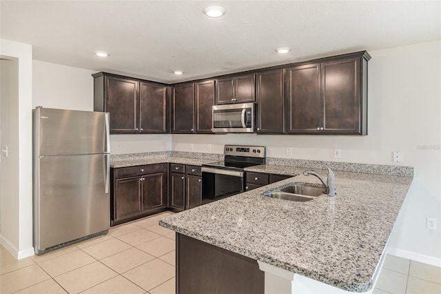 kitchen with stainless steel appliances, kitchen peninsula, dark brown cabinetry, and sink