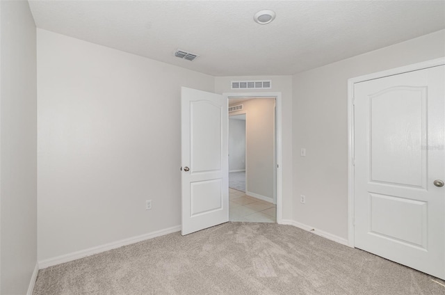 unfurnished bedroom featuring a textured ceiling and light colored carpet