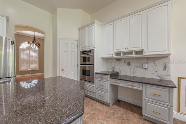 kitchen with dark stone counters, white cabinets, a chandelier, and appliances with stainless steel finishes