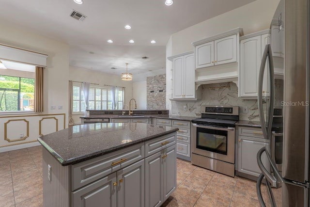 kitchen featuring a kitchen island, appliances with stainless steel finishes, decorative backsplash, and a healthy amount of sunlight