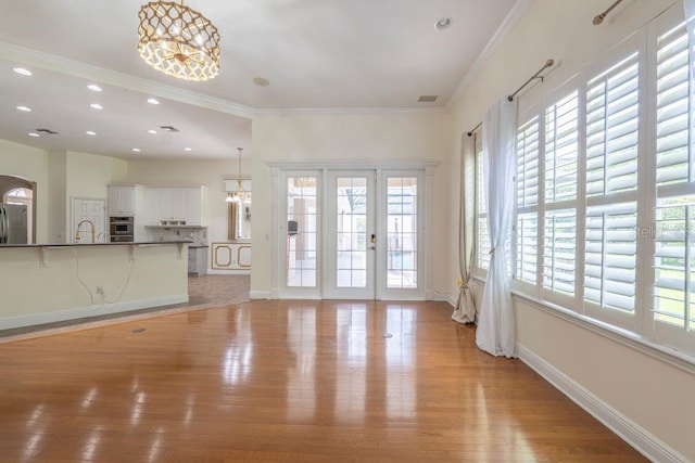 unfurnished living room with light hardwood / wood-style flooring, a wealth of natural light, and crown molding